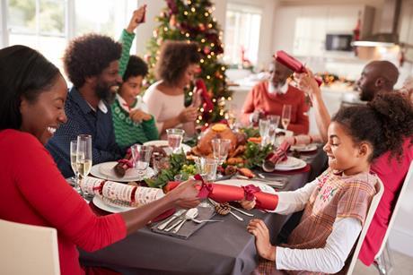 Family Christmas dinner, with people at the table pulling crackers