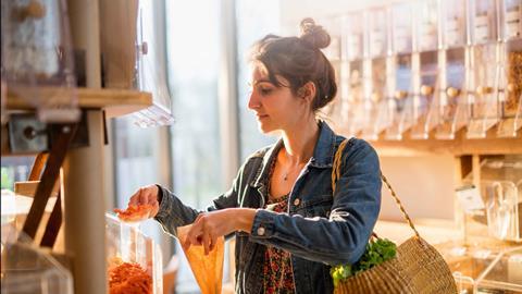 Woman in a shop filling a brown paper bag with cereal