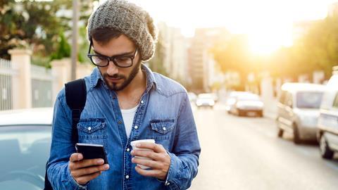 Young man in street with coffee and phone