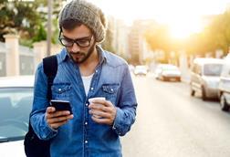 Young man in street with coffee and phone