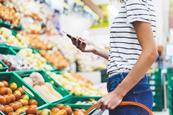 Female shopper in supermarket with basket, shown from head down