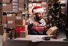 Man in Santa hat and Christmas jumper scanning parcel