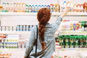 Woman lifting a product from a supermarket shelf