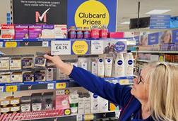 Woman reaching for a product inTesco with a sign reading: 'MTick – Menopause friendly'