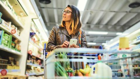 Woman shopping in supermarket and looking at phone