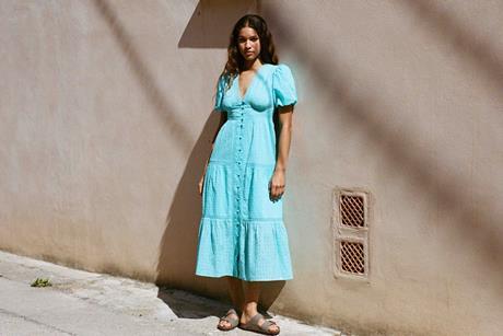 Model wearing Nobody's Child dress and standing by a wall in sunshine