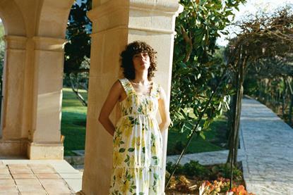 Model wearing Nobody's Child clothing and leaning against a pillar outdoors