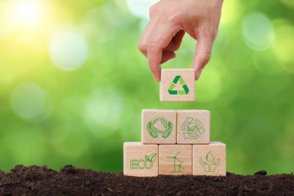 Hand stacking blocks with symbols related to sustainability