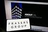 Frasers Group logo on a phone in front of a computer showing Frasers Group website