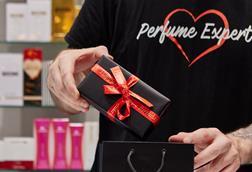 The Perfume Shop employee shown from the neck down putting a package in a gift bag