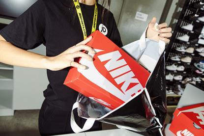 Store worker putting Nike trainers in JD Sports bag