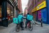 Two Deliveroo riders on a street in Manchester