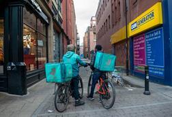 Two Deliveroo riders on a street in Manchester