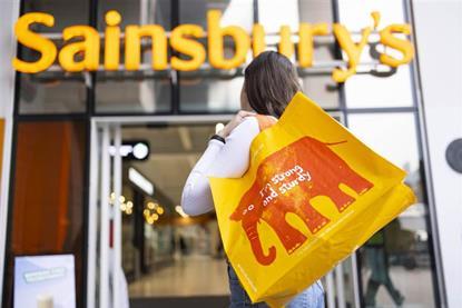 Woman holding Sainsbury's reusable bag and heading into Sainsbury's store