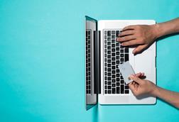 Overhead image of a person's hands at a laptop holding a credit card