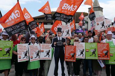 Asda workers on strike with flags and a cutout of TDR capital Manjit Dale